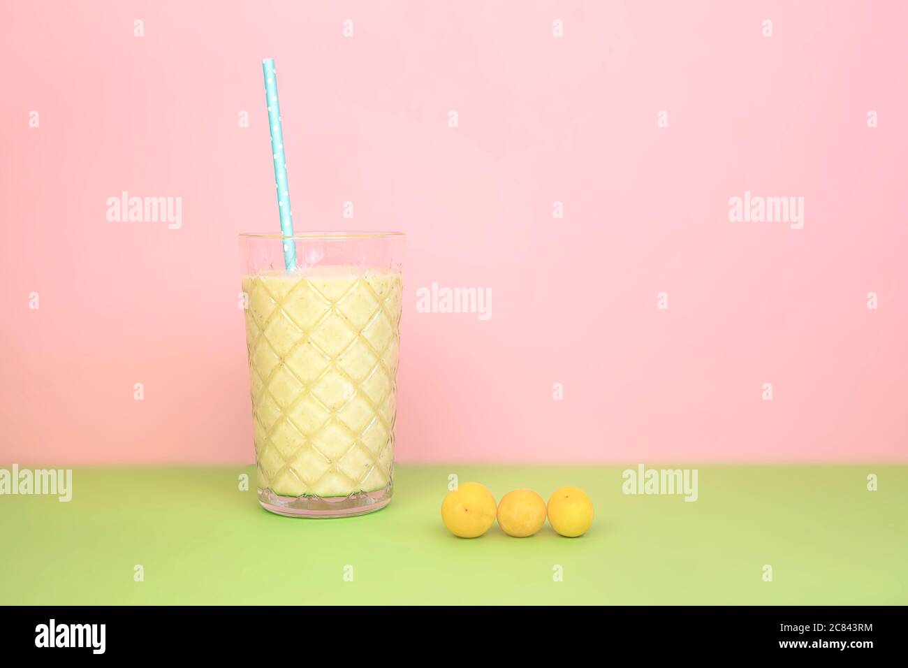 Pflaumenfrucht Shake im Glas mit Stroh auf rosa, grünen Hintergrund. Sommer, gesundes Getränk. Stockfoto