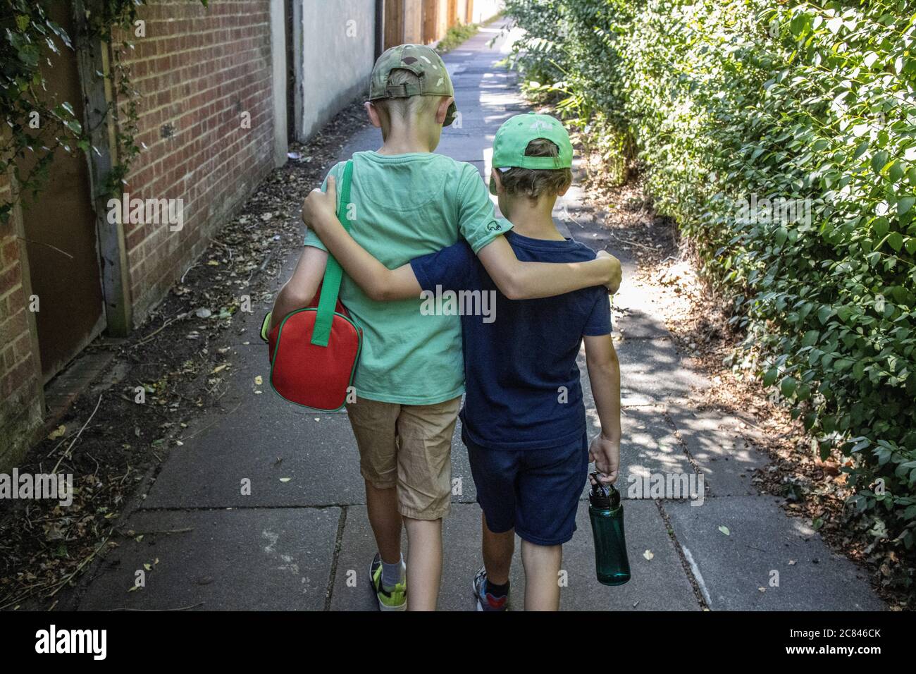 Brüderliche Liebe, zwei junge Brüder gehen zusammen, Arme um einander Schultern, London, England, Vereinigtes Königreich Stockfoto