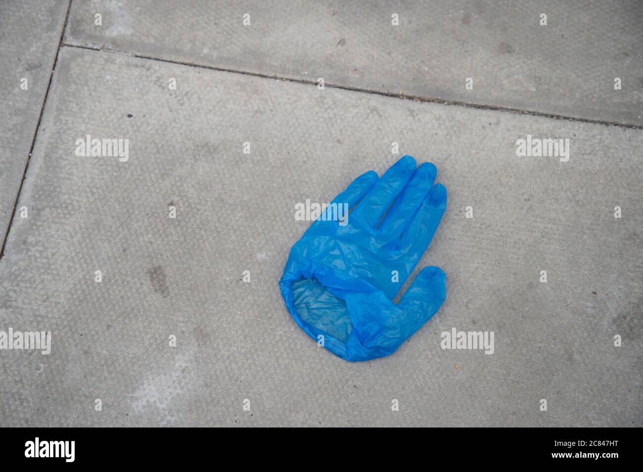 Hackney, London, Großbritannien. Ein ausrangierte blaue Einweghandschuh auf dem Bürgersteig. Stockfoto