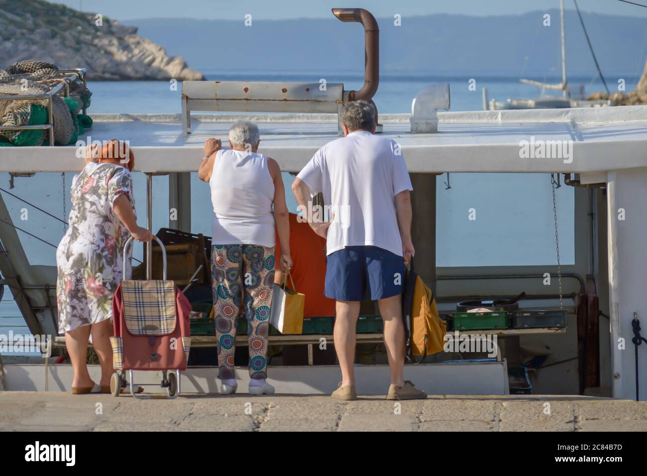 Käufer wählen frisch gefangenen Fisch auf Fischerboot in Makarska Kai, Kroatien dockt Stockfoto