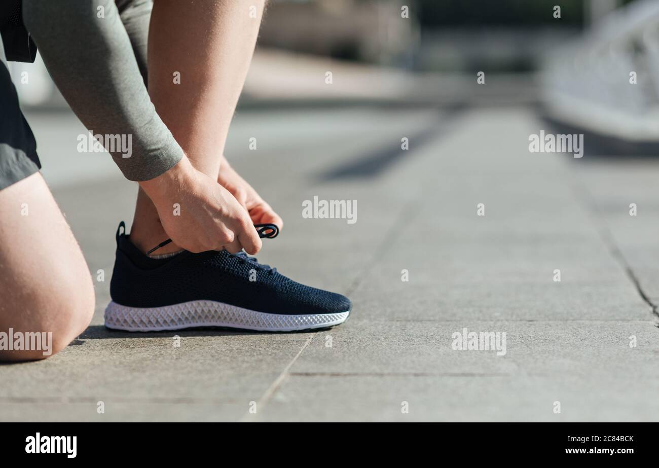 Machen Sie sich bereit für das Training. Kerl schnürt Sneakers im Stadion Stockfoto