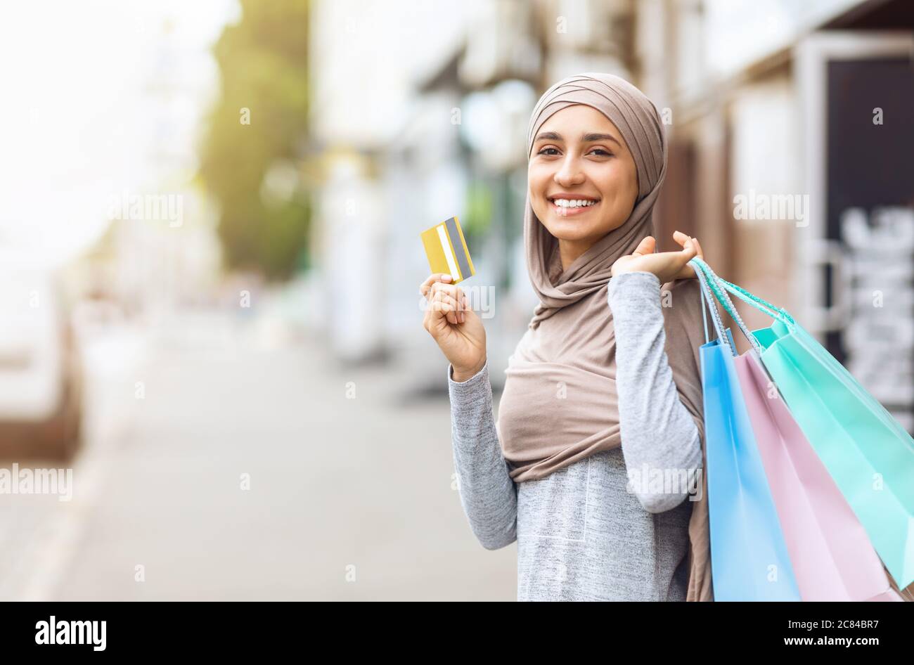 Aufgeregt muslimische Mädchen mit Einkaufstaschen zeigen Kreditkarte Stockfoto