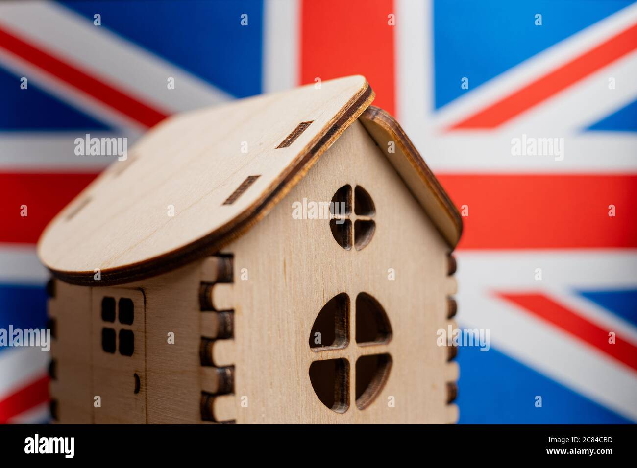 Kleines Holzhaus, Flagge Großbritanniens auf Hintergrund. Immobilienkonzept, Soft Focus Stockfoto