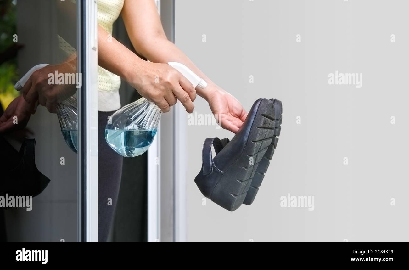 Frau ziehen ihre Schuhe aus und reinigen mit Alkohol, bevor sie ein Haus zum Schutz der infizierten Covid-19 betreten Stockfoto