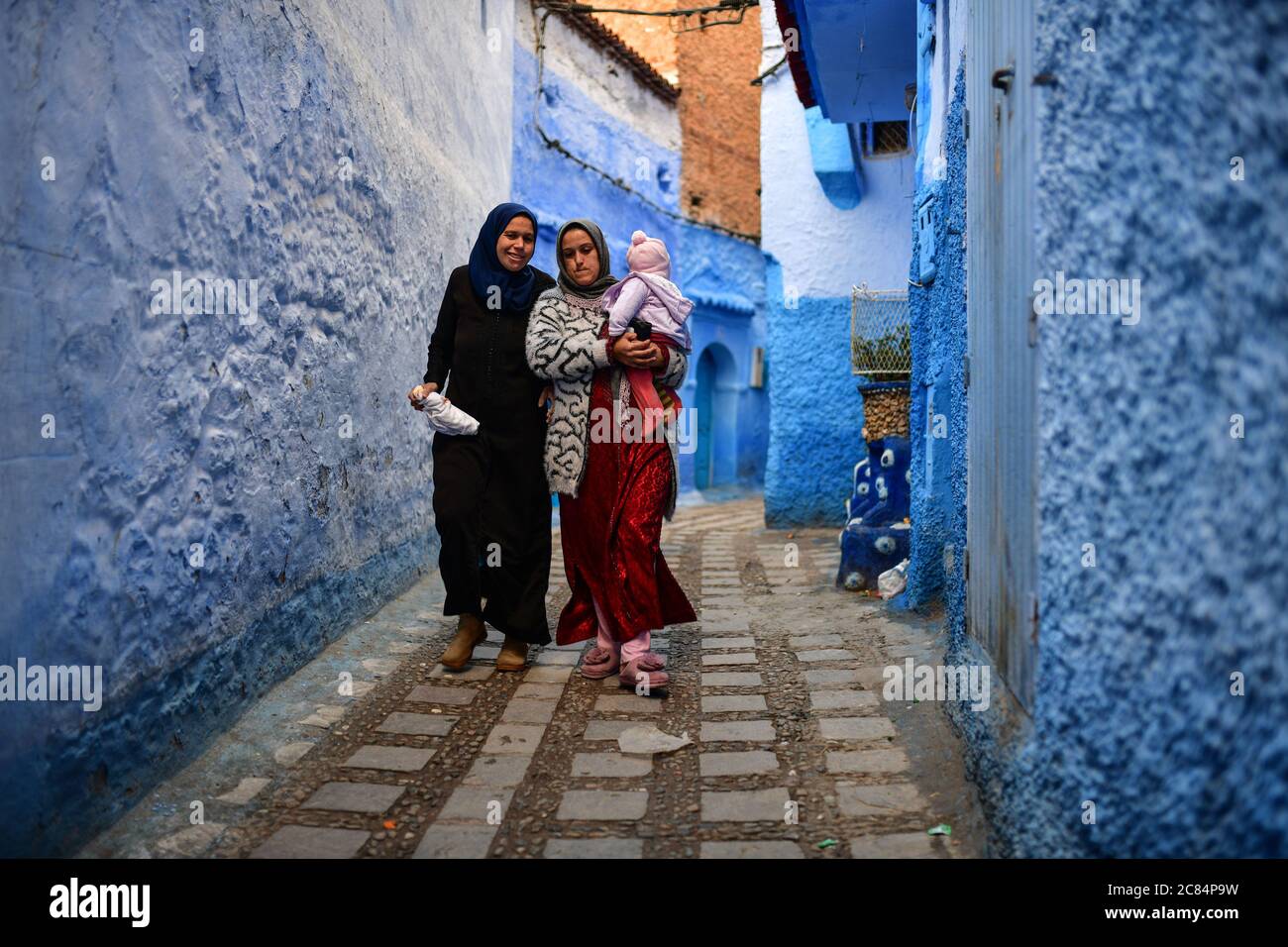 Marokko, Chefchaouen : zwei verschleierte Frauen mit einem Kind, die in einer Straße der Altstadt spazieren. Gefliester Fußboden Stockfoto