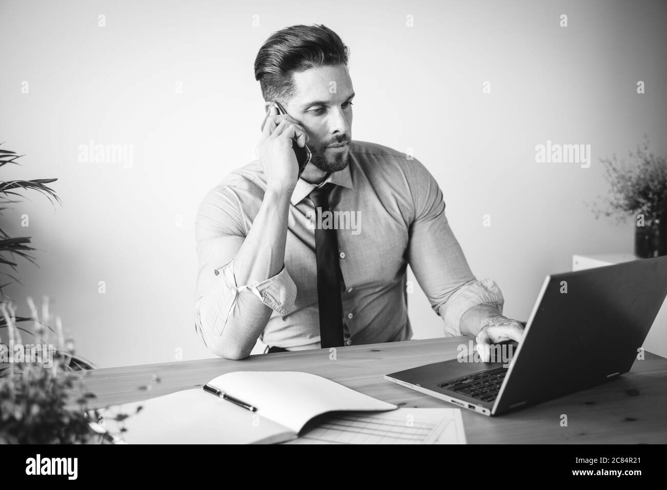 Junger Geschäftsmann, der in seinem Büro arbeitet und Kaffee trinkt Stockfoto