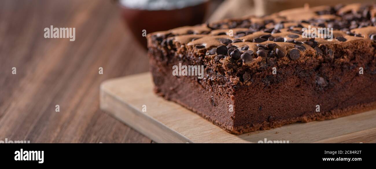 Schokoladengeschmack taiwanesische traditionelle Biskuitkuchen (taiwanesische castella kasutera) auf einem Holztablett Hintergrund Tisch mit Zutaten, close up. Stockfoto