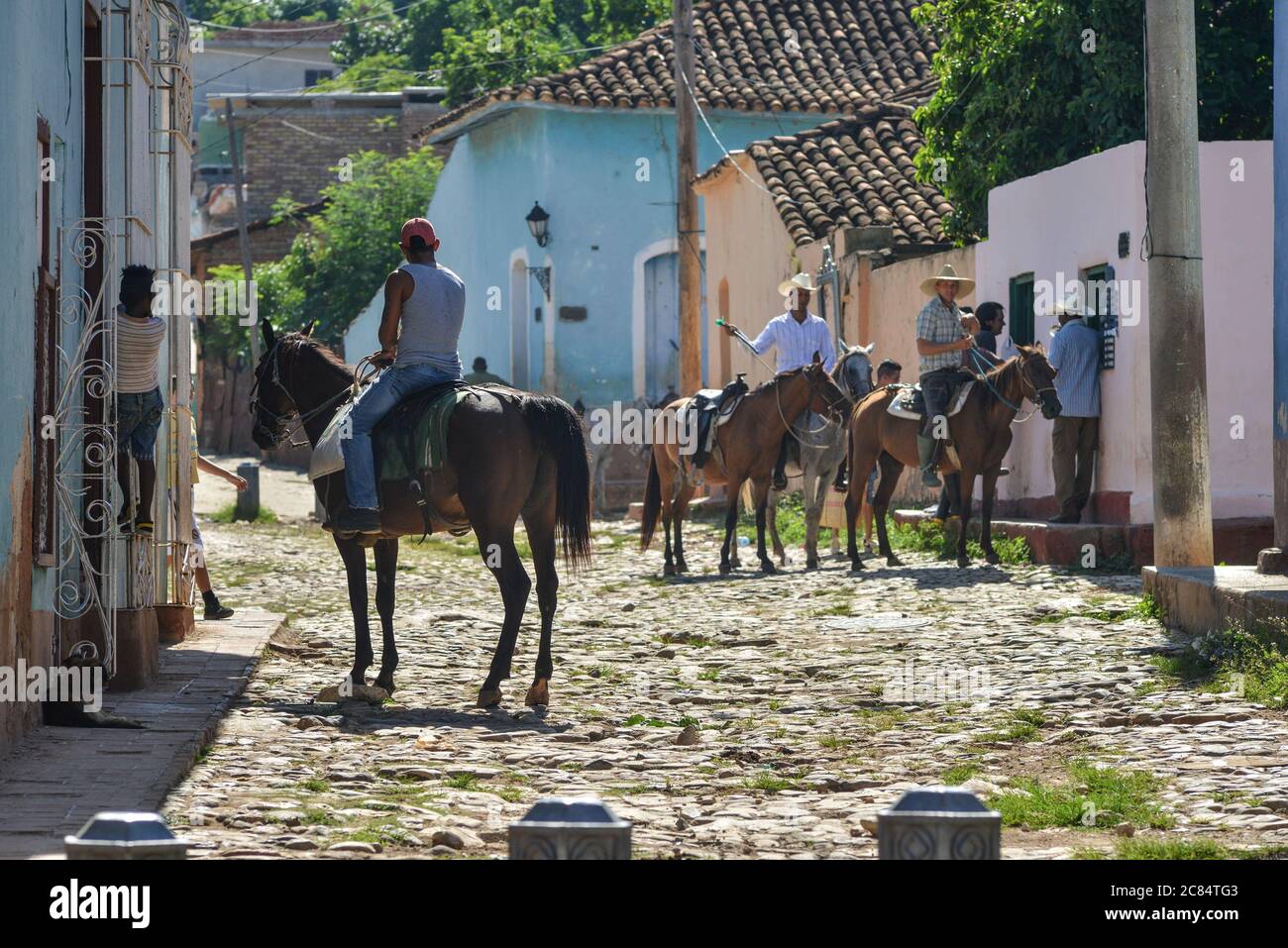 Kuba, Sancti Spiritus Provinz: Trinidad. Szene aus dem Alltag. Männer mit Cowboy-Hüten, zu Pferd, im Gespräch mit einem anderen Mann vor der Haustür von Hi Stockfoto