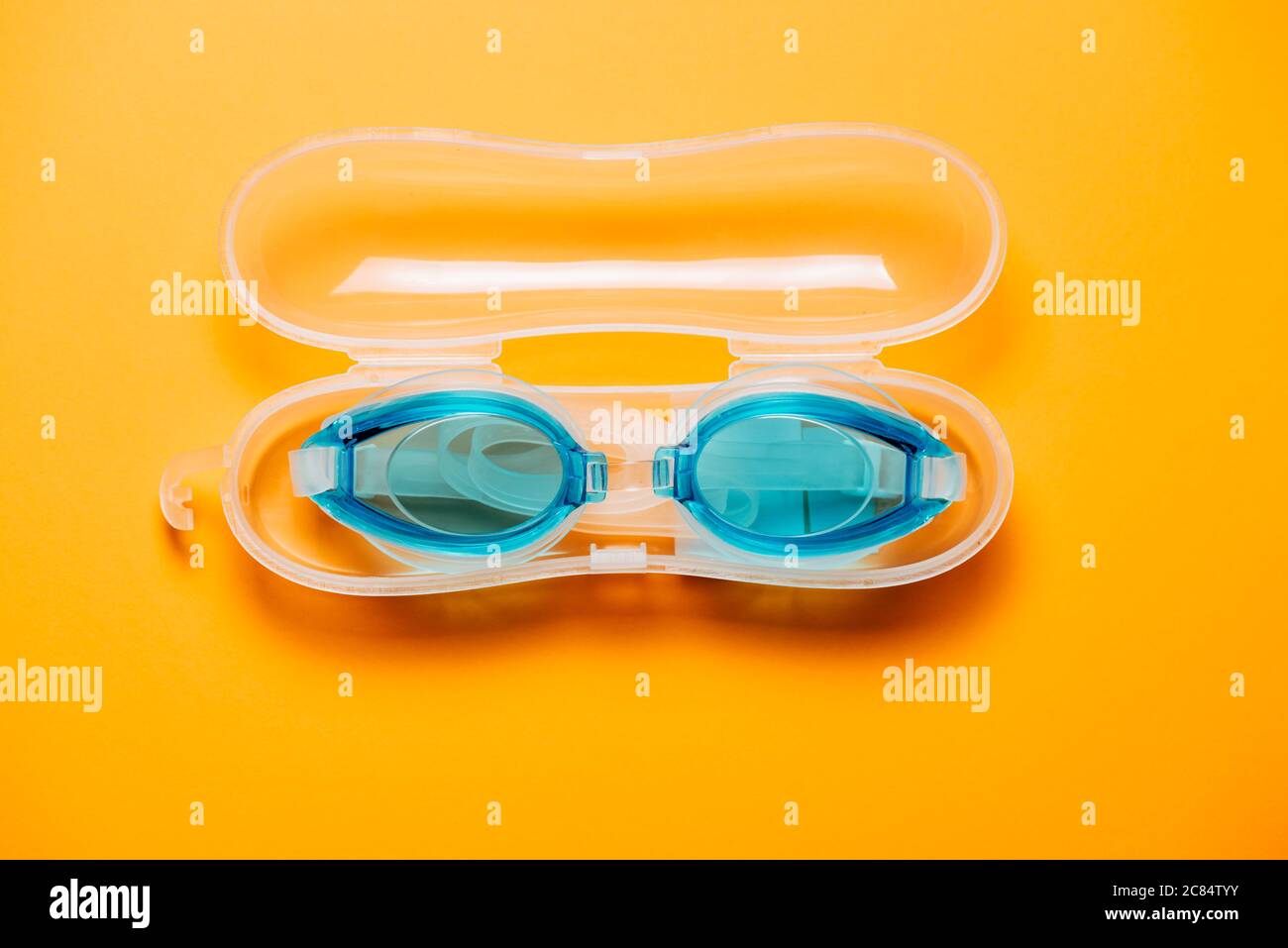 Blaue Schwimmbrille, mit Gummiband im Kunststoffkoffer, auf gelbem Hintergrund. Niemand, Produktkonzept Stockfoto