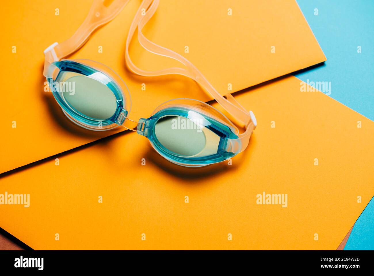 Blaue Schwimmbrille mit Gummiband auf gelbem geometrischen Hintergrund. Niemand, Produktkonzept Stockfoto