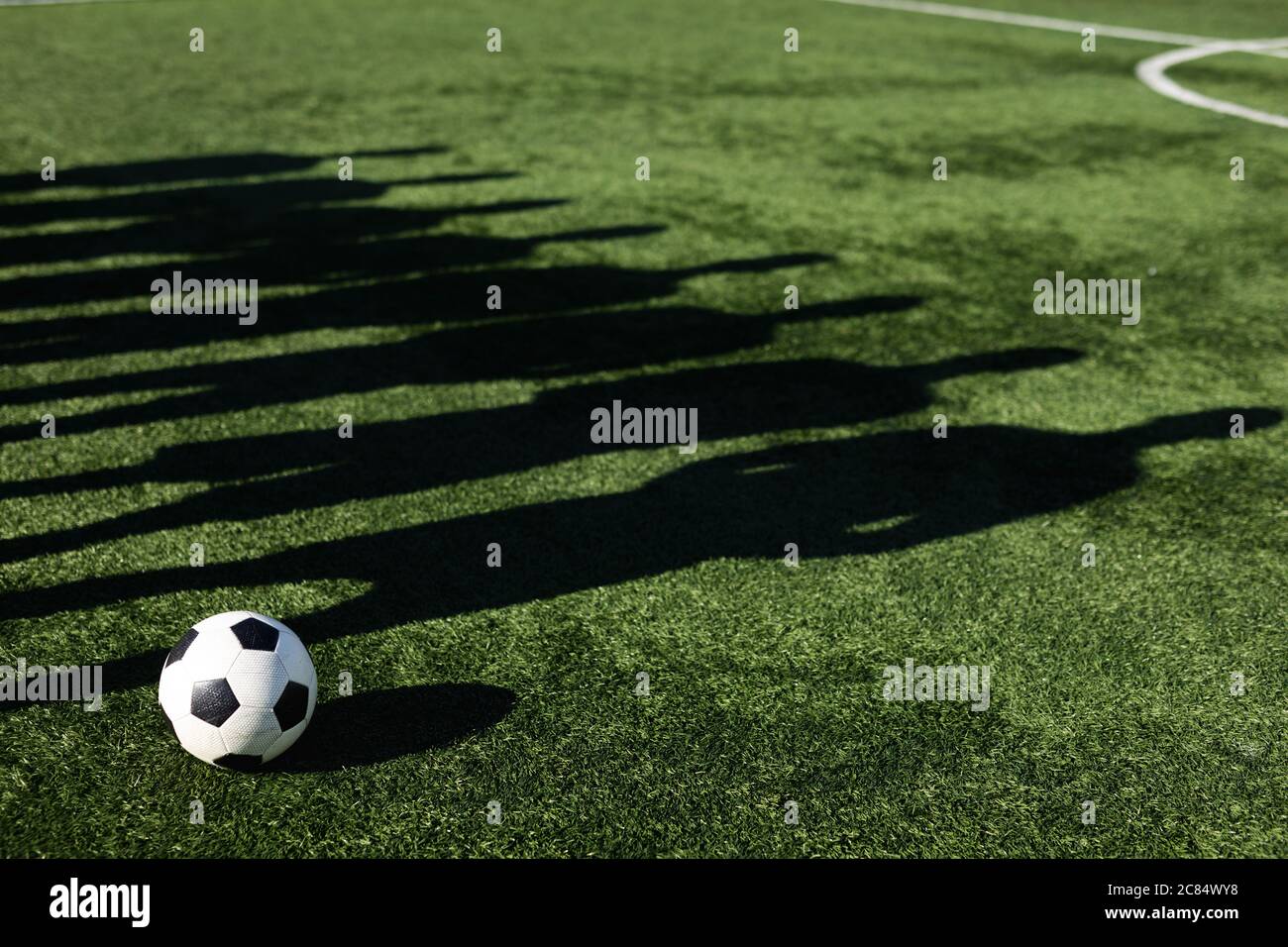 Schatten auf Rasen der Gruppe der männlichen Fußballspieler Training auf einem Sportplatz in der Sonne, neben einander stehend Ball neben ihnen. Stockfoto
