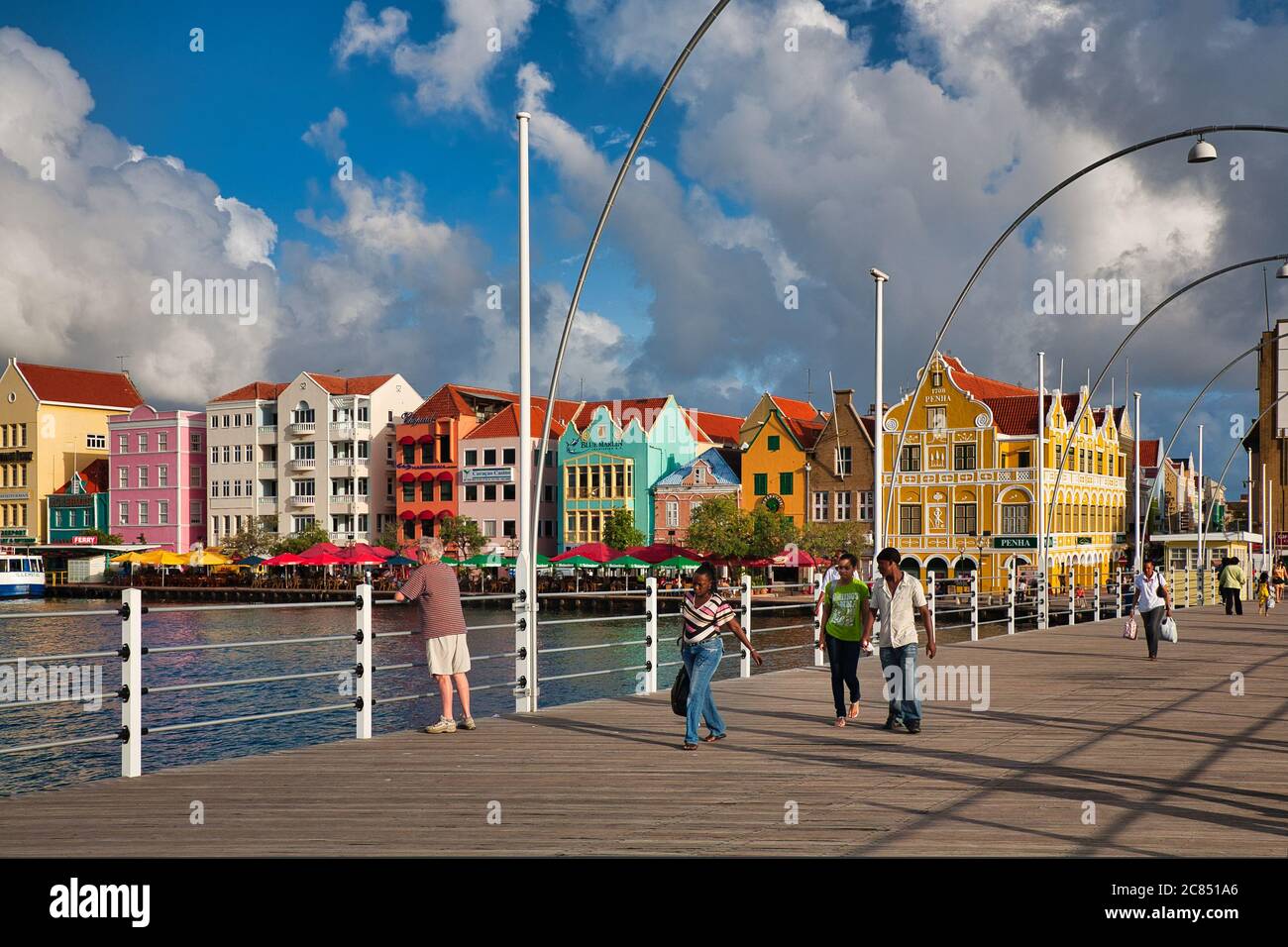 Menschen, die über die Queen Emma Brücke mit typisch holländischen Gebäuden im Hintergrund, Willemstat, Curacao, Karibik, West Indies Stockfoto