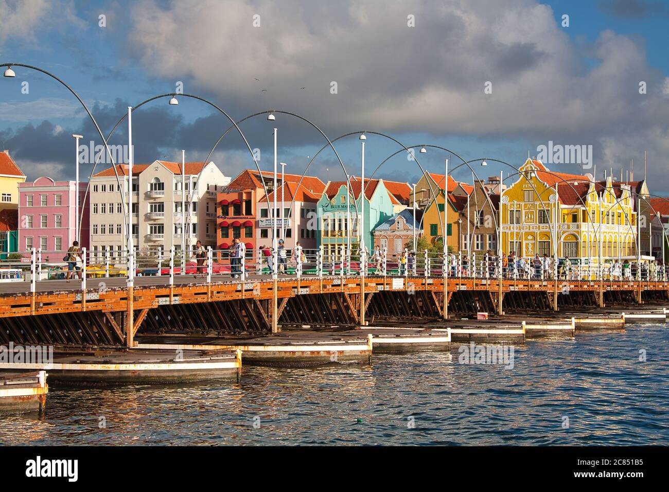 Menschen, die über Queen Emma Swing Bridge mit typisch holländischen Gebäuden im Hintergrund, Willemstat, Curacao, Karibik, West Indies Stockfoto
