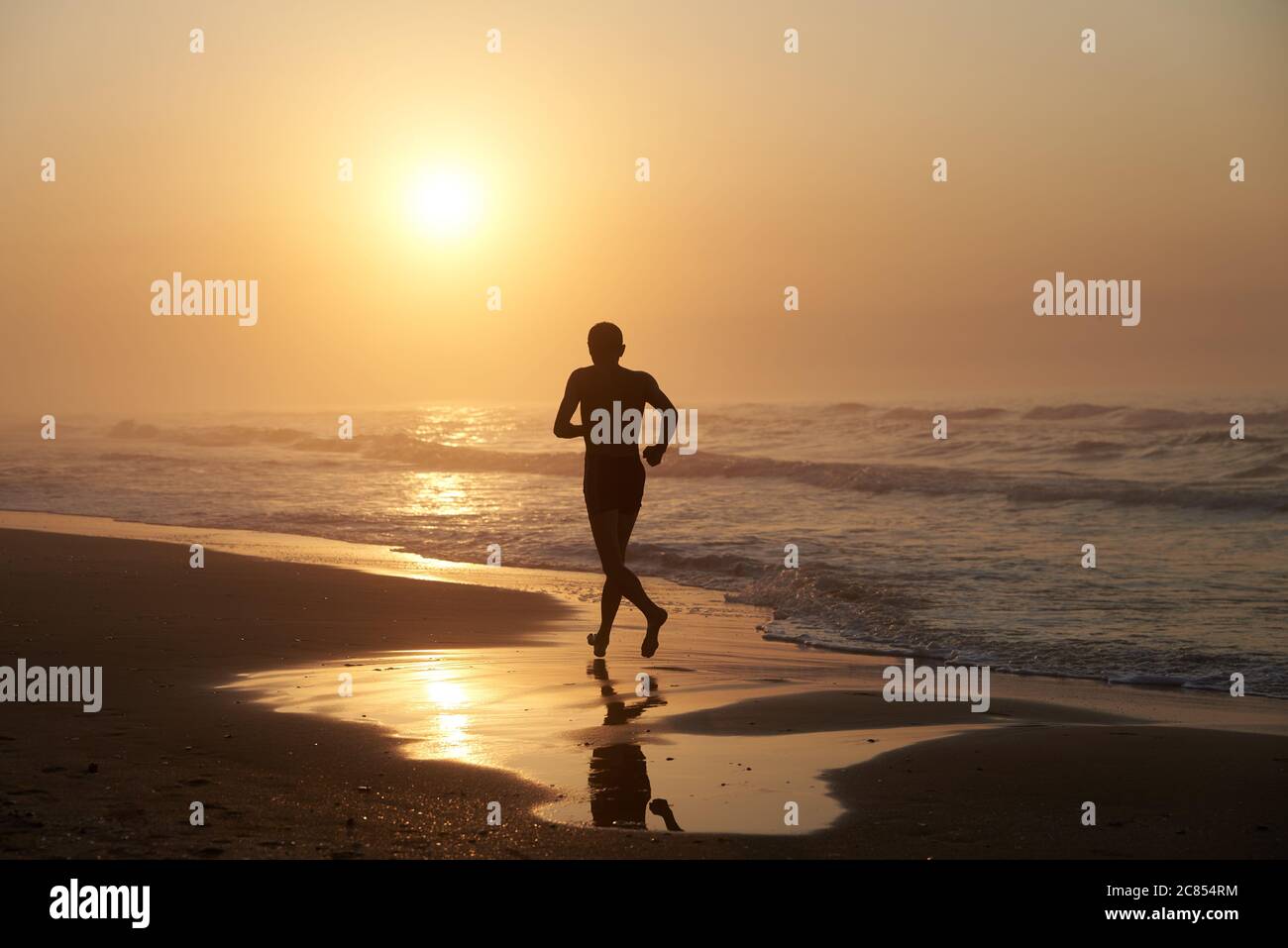 Ein Mann, der am Morgen entlang der Küste des Meeres läuft Stockfoto