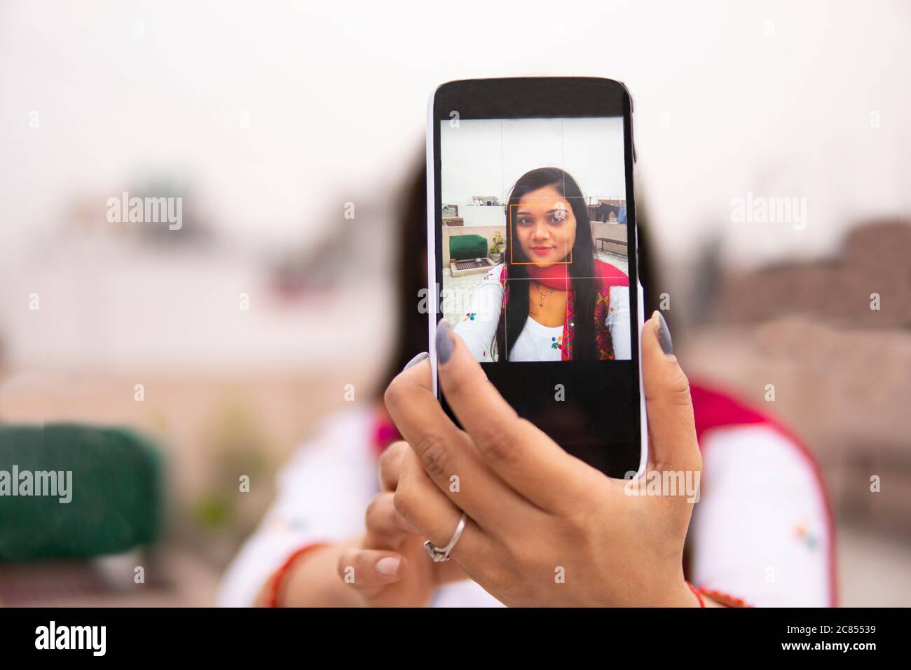 Schöne, glückliche indische junge Frau, die Selfie über das Smartphone macht und die Kamera anschaut. Sie trägt traditionelle Kleidung Salwar Kameez. Stockfoto