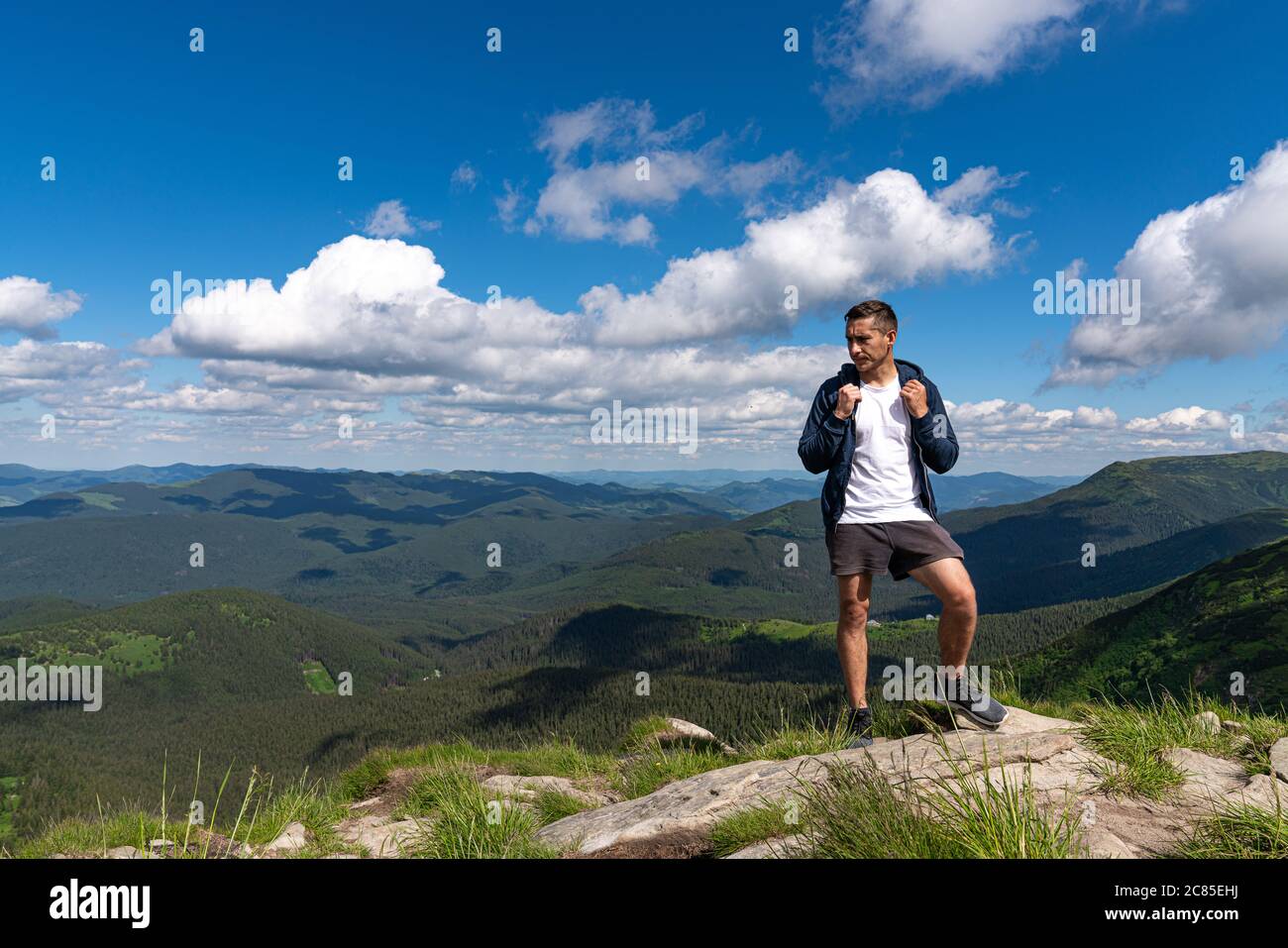 Aufgeregt Mann Wandern auf einem Berggipfel mit Rucksack genießen Sie die Aussicht und auf der Suche nach Abenteuern Stockfoto
