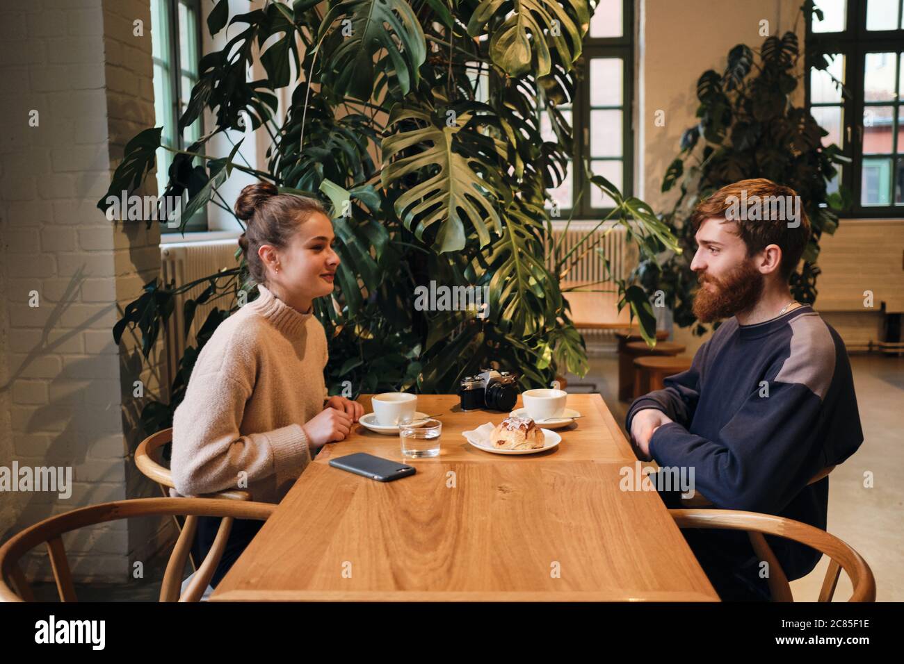Seitenansicht des jungen schönen Paares, das sich beim Kaffee im Café verträumt anschaut Stockfoto
