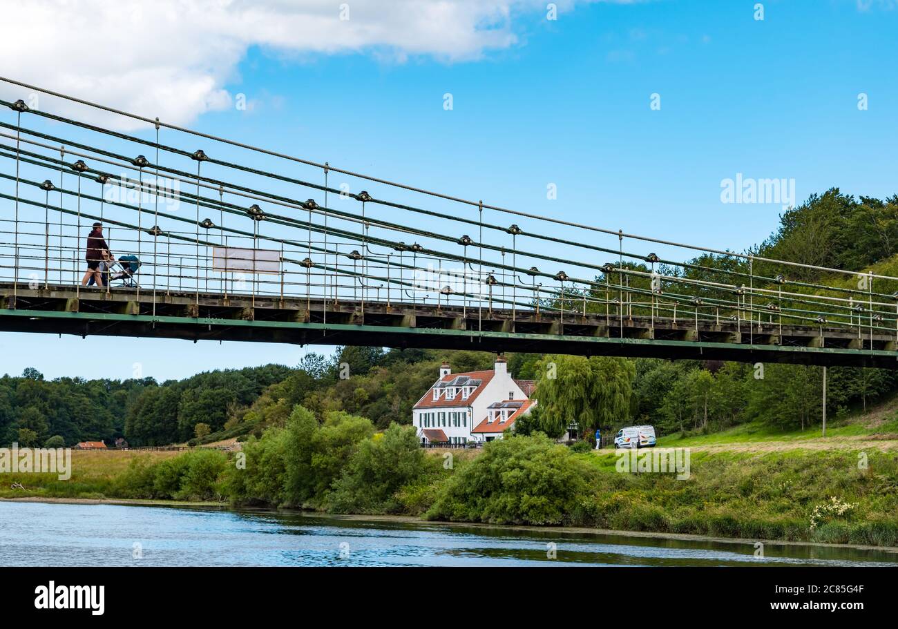 River Tweed, Englisch/Schottische Grenze, Großbritannien, 21. Juli 2020. 200 Jahre Union Bridge: Die Brücke feiert am 26. Juli ihr 200-jähriges Bestehen. Es war die erste Fahrzeugaufhängung Brücke in Großbritannien. Zur Zeit ihrer Errichtung war sie mit 137 m die längste schmiedeeiserne Hängebrücke der Welt. Es wird immer noch regelmäßig von Fußgängern, Radfahrern und Autos verwendet, aber Autos müssen es zu einer Zeit überqueren. Diese Ansicht ist vom Flussufer an der schottischen Grenze Stockfoto