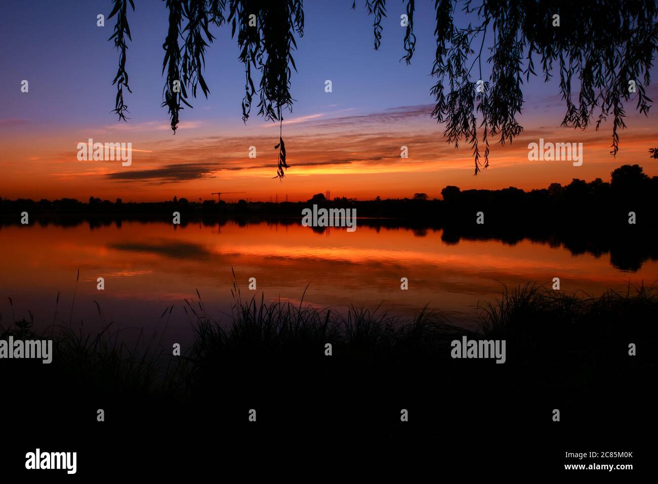 Symmetrie des Himmels in einem See bei Sonnenaufgang. Wolken, die sich auf dem Wasser spiegeln. Ferienlandschaft am Meer. Ruhige entspannende Szene mit einem schönen bunten Stockfoto
