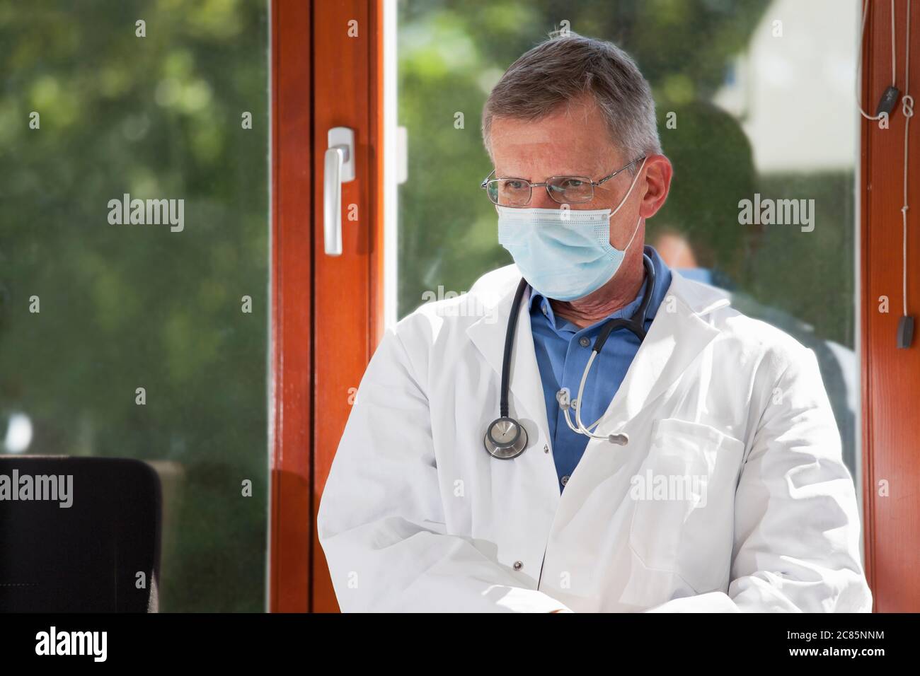 Porträt eines müden oder erschöpften Arztes, der in einem hellen Wartezimmer eines Krankenhauses oder einer Klinik sitzt - Fokus auf das Gesicht Stockfoto