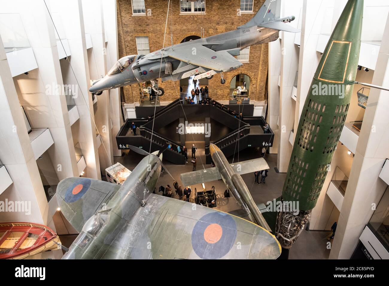 Imperial war Museum Aircraft Display London // LONDON, Vereinigtes Königreich — Ein dramatischer Blick auf Militärflugzeuge, die im zentralen Atrium des Imperial war Museum London aufgehängt sind. Das neu gestaltete Atrium des Museums zeigt historische Flugzeuge aus verschiedenen Konflikten und schafft eine eindrucksvolle visuelle Ausstellung, die Besucher in die britische Geschichte der militärischen Luftfahrt einführt. Die Kollektion umfasst legendäre Flugzeuge wie die Supermarine Spitfire, die während des Zweiten Weltkriegs eine entscheidende Rolle in der Schlacht um Großbritannien spielte, und den Harrier Jump Jet, der für seine vertikale Start- und Landekapazität bekannt ist Stockfoto