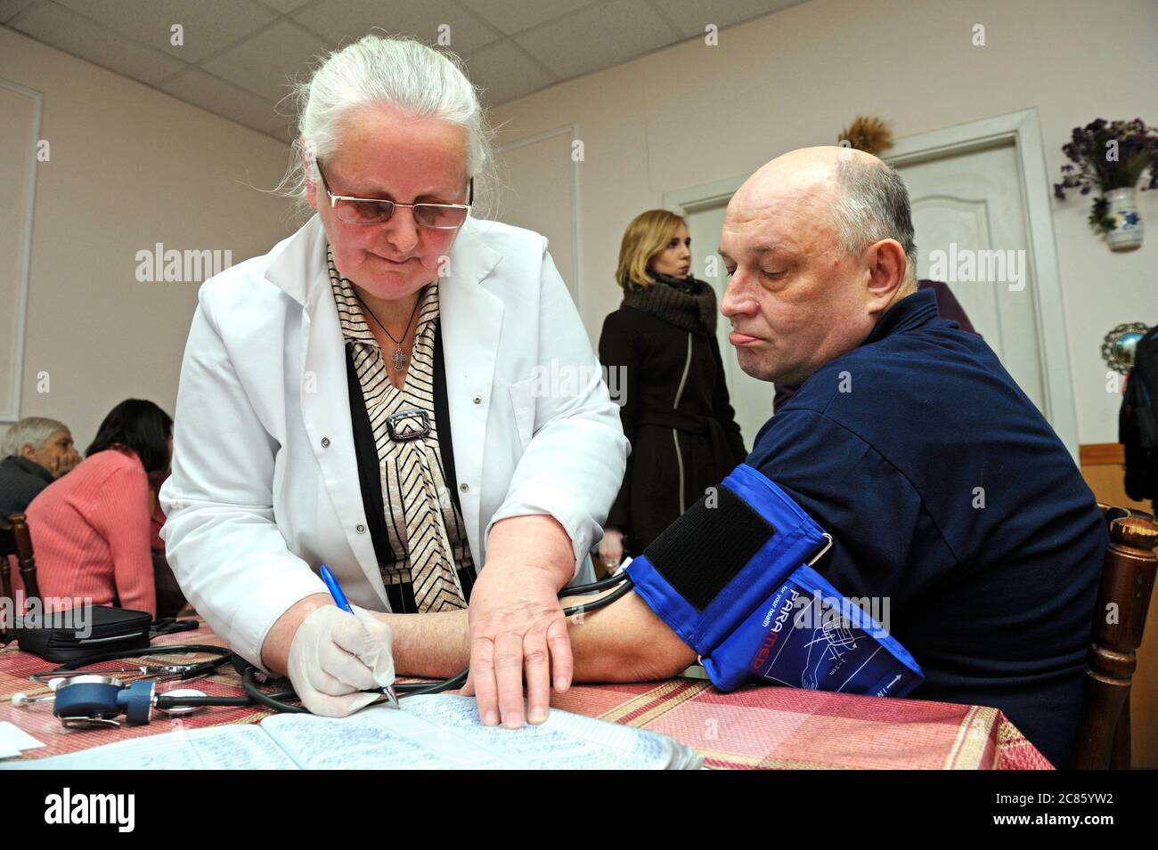 Sanitäter, der Blutdruck und Herzfrequenz mit Tonometer eines Patienten nimmt. Eröffnung des Pecherski Zentrums der sozialen Dienste. April 2018. Kiew, Ukra Stockfoto