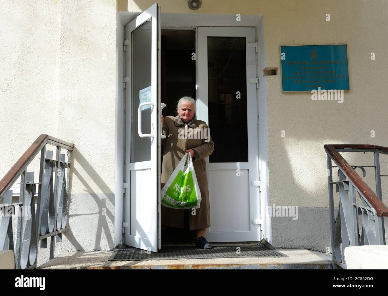 Alte Frau verlässt das Gebäude des Zentrums der sozialen Dienste, Zeichen und Tür des Zentrums. Eröffnung des Zentrums der sozialen Dienste von Pechersky distr Stockfoto