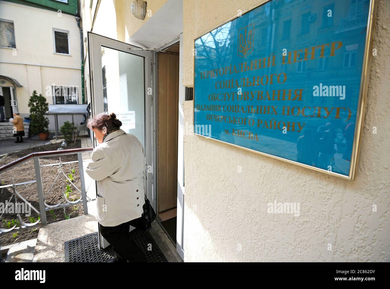 Alte Frau verlässt das Gebäude des Zentrums der sozialen Dienste, Zeichen und Tür des Zentrums. Eröffnung des Zentrums der sozialen Dienste von Pechersky distr Stockfoto
