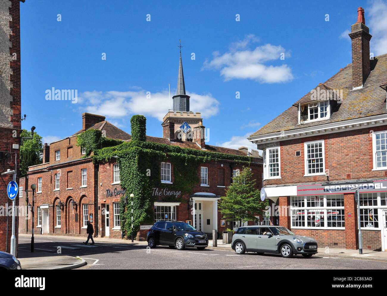 Hitchin Street, (mit 'The George' an der Ecke Church Street und der Kirche dahinter), Baldock, Hertfordshire, England, Großbritannien Stockfoto