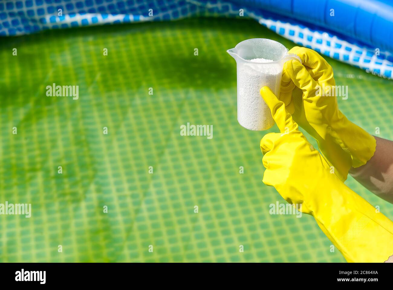 Zugabe von Chlorpulver für den Pool, um Algen zu entfernen und Wasser zu desinfizieren. Aufblasbares Schwimmbad Pflegekonzept. Stockfoto