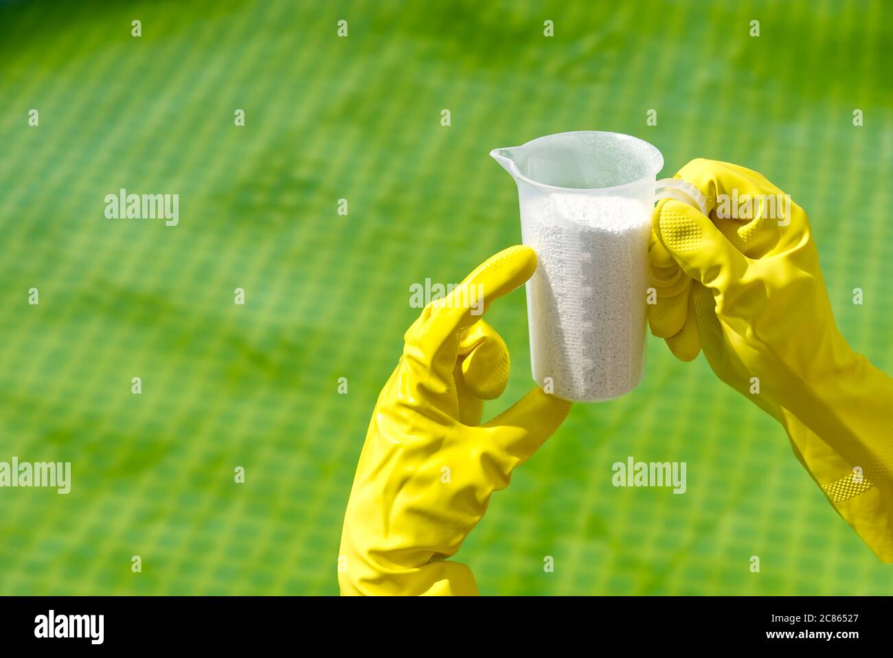 Zugabe von Chlorpulver für den Pool, um Algen zu entfernen und Wasser zu desinfizieren. Aufblasbares Schwimmbad Pflegekonzept. Stockfoto