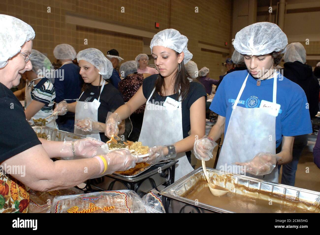 San Antonio, Texas USA, 24. November 2005: Hispanische High School Teens stellen Essen auf Teller beim jährlichen Raul Jiminez Thanksgiving Dinner, wo mehr als 25.000 Mahlzeiten am Thanksgiving Day für ältere Menschen, Obdachlose, Arme und Vertriebene aus Südtexas serviert werden. Die Veranstaltung, die vom verstorbenen Restaurantbesitzer Raul Jiminez ins Leben gerufen wurde, findet im 26. Jahr statt. ©Bob Daemmrich Stockfoto