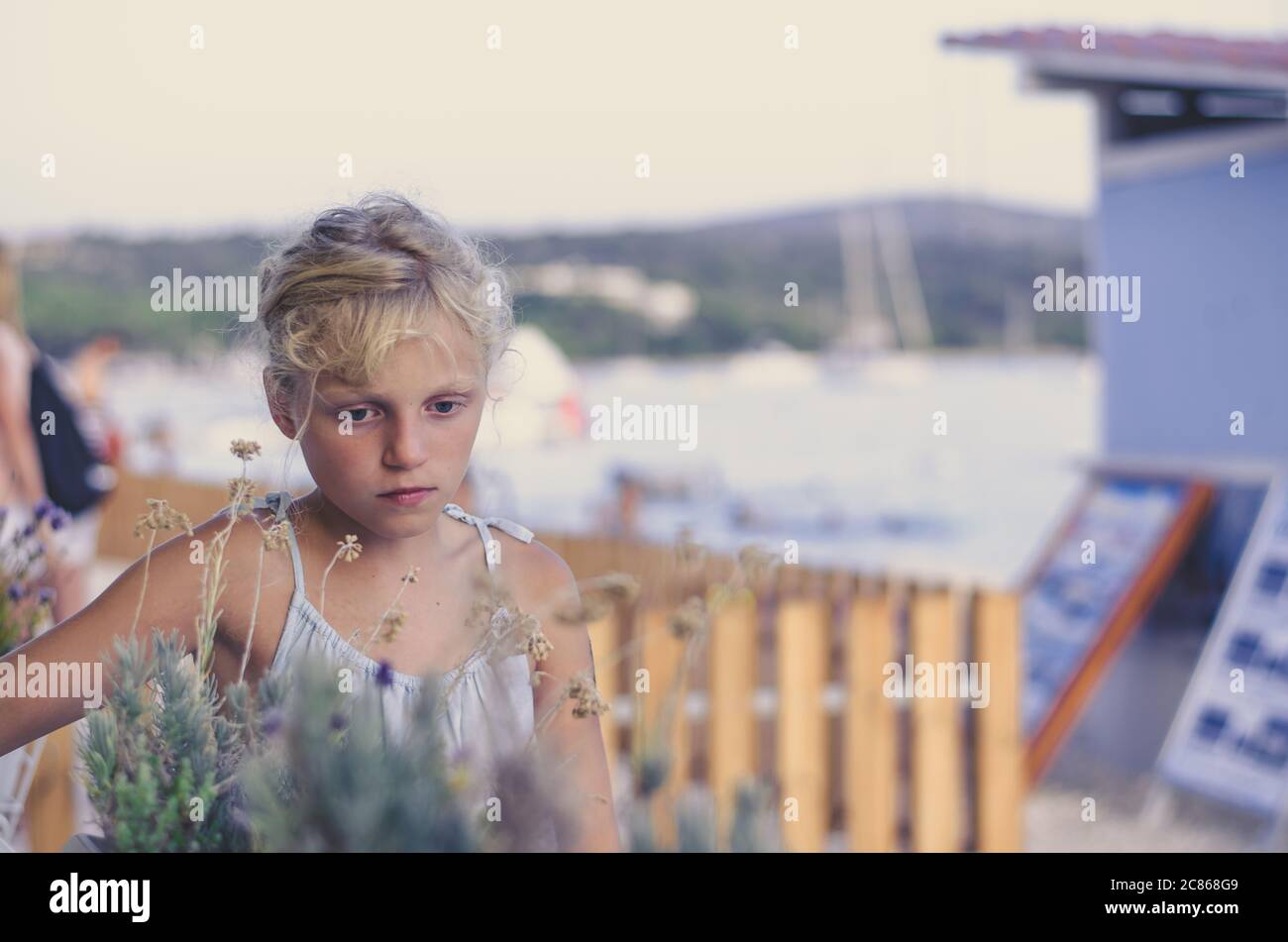 Nette kleine blonde Mädchen in blauem Kleid Porträt in blau matt Ton Atmosphäre Stockfoto