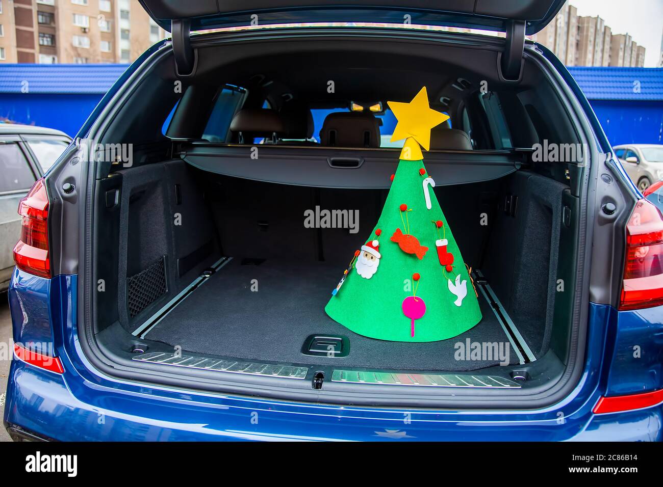 Besuchen Sie Familie in Neujahr Urlaub Konzept. Ein mit Spielzeug und einem Stern geschmückter Weihnachtsbaum aus Filz steht im leeren Kofferraum eines Stockfoto