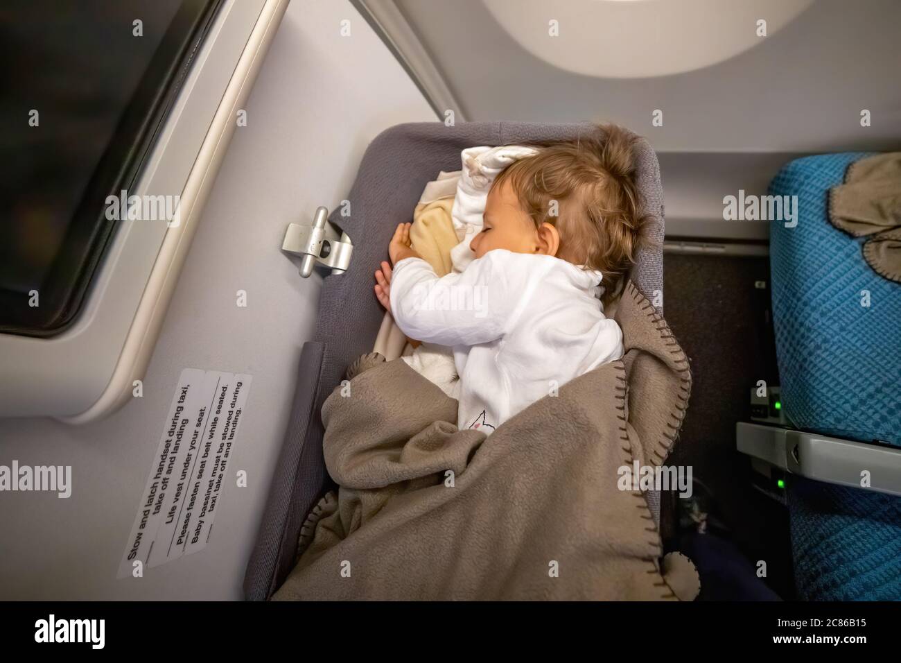 Der Kleinkinder schläft sicher und komfortabel im Baby Bussinet auf einem langen Flug. Stockfoto