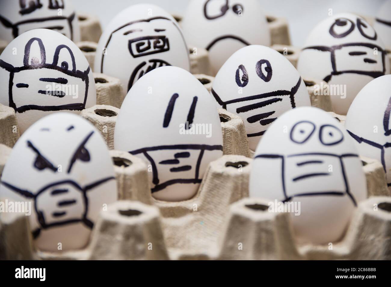 Nahaufnahme von verschiedenen Huhn ostereier mit Doodle emotionale Gesichter tragen medizinische Masken mit weißem Hintergrund Stockfoto