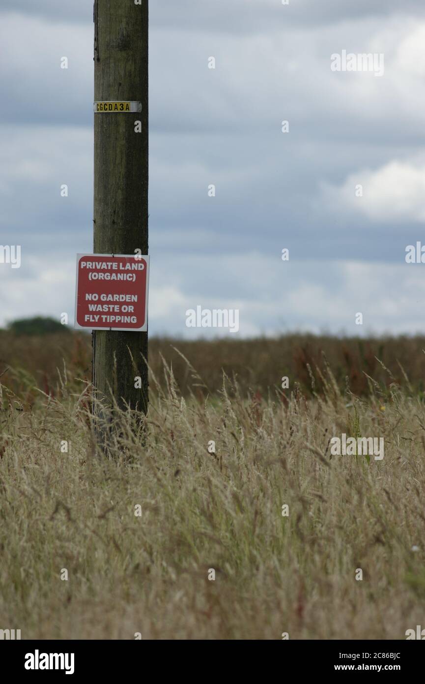 Ein Schild auf Telegrafenmast zeigt Private Land ( organisch) & No Fly Tipping oder Gartenabfälle auf Ackerland in Tetbury, Gloucestershire UK Stockfoto