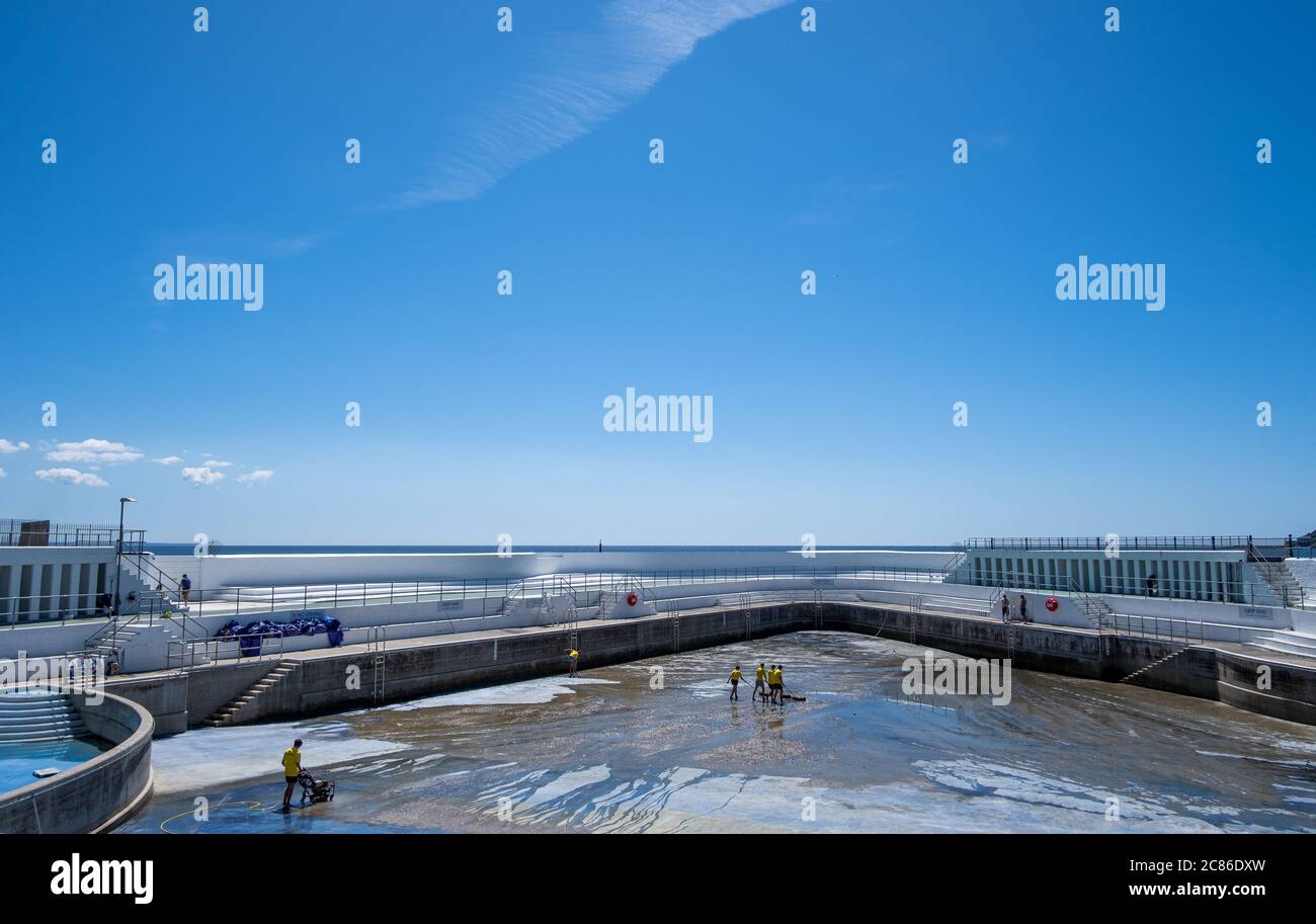 Rettungsschwimmer reinigen Algen auf dem Boden des Jubilee Pool, Penzance; vor der Wiederfüllung und Wiedereröffnung am 25. Juli 2020 nach dem Coronavirus Lockdown. Stockfoto