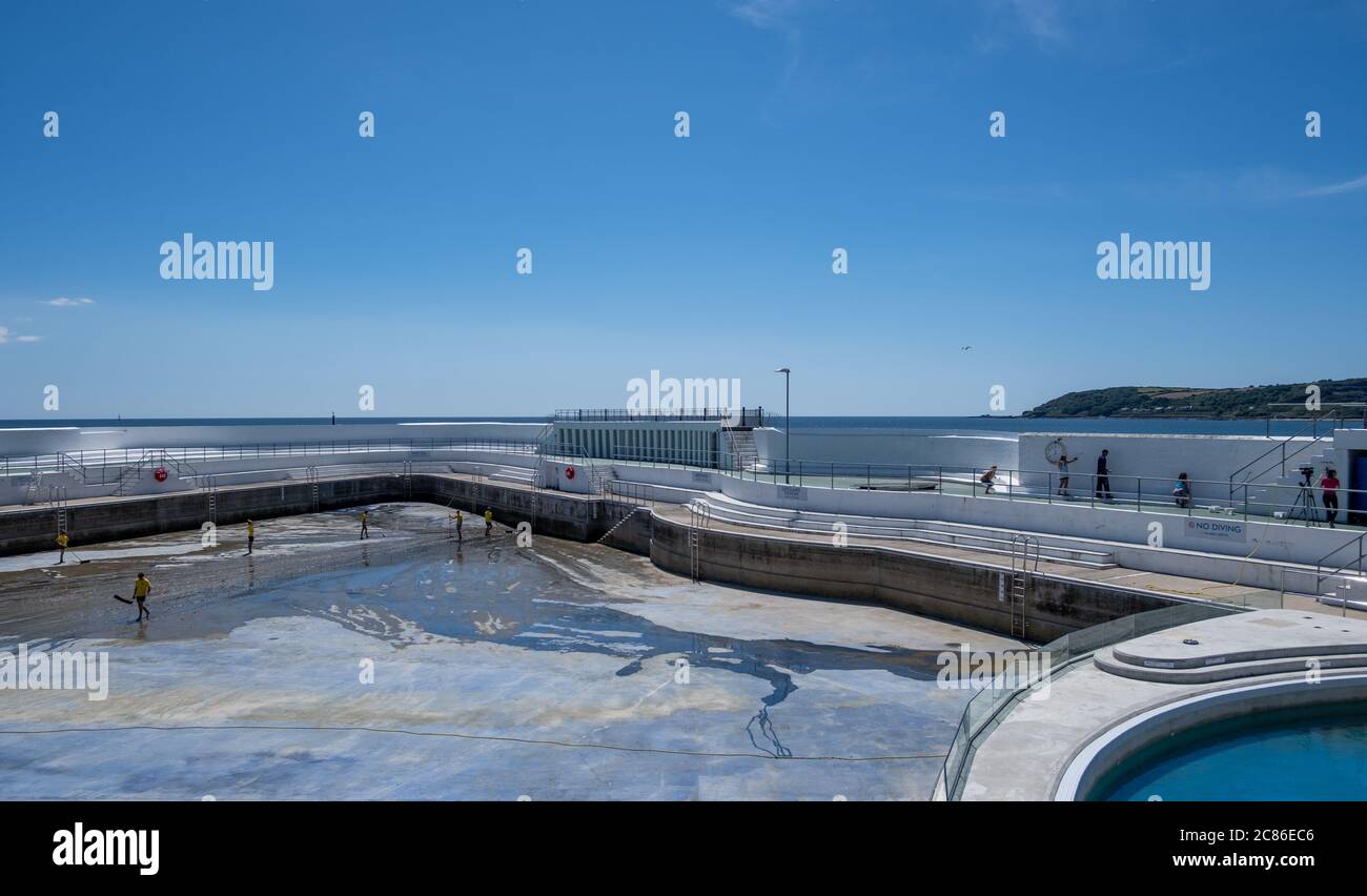 Rettungsschwimmer reinigen Algen auf dem Boden des Jubilee Pool, Penzance; vor der Wiederfüllung und Wiedereröffnung am 25. Juli 2020 nach dem Coronavirus Lockdown. Stockfoto