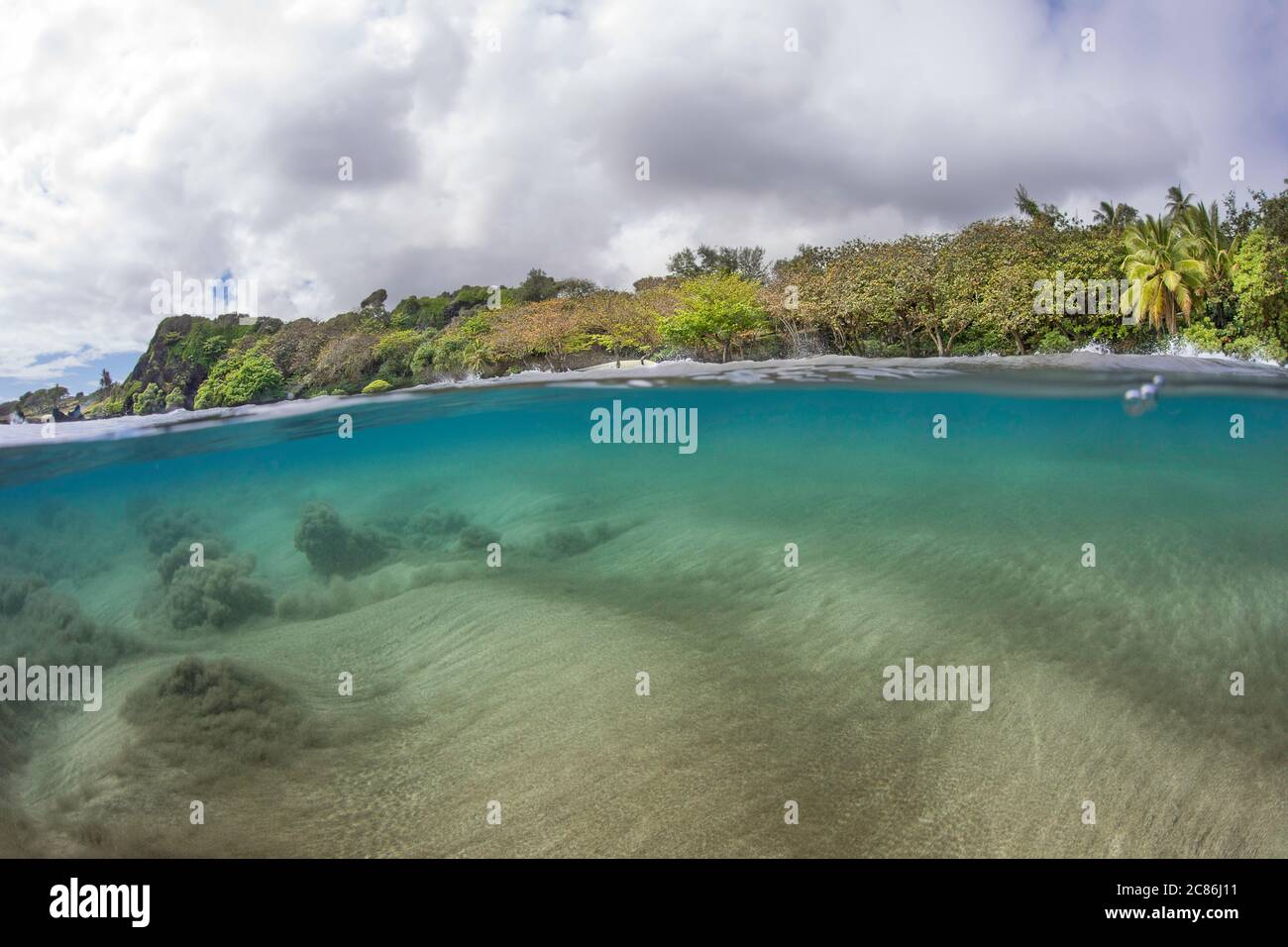 Surf schiebt den Sandboden auf, während eine Welle sich auf Homoa Beach, Hana, Maui, Hawaii bewegt. Stockfoto