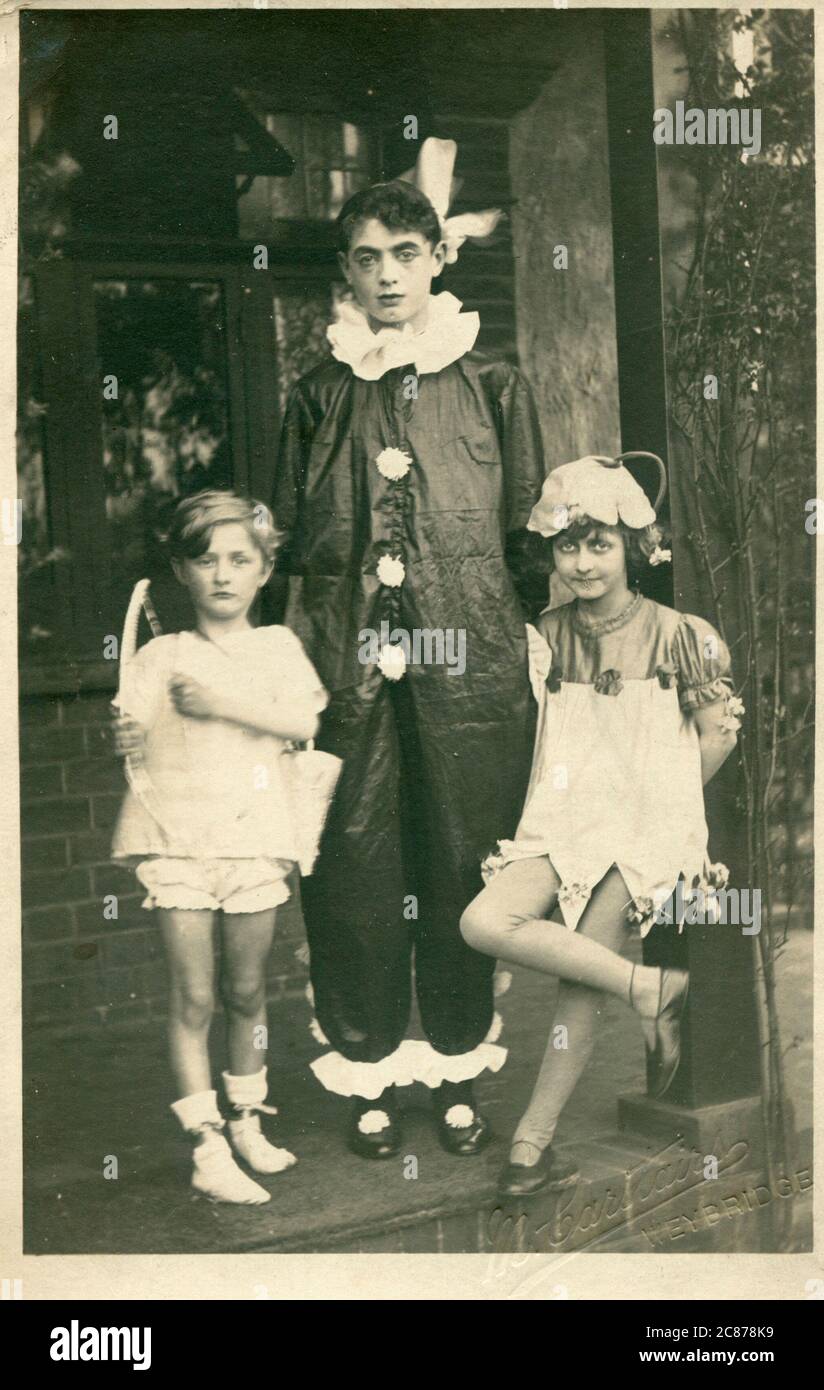 Drei Kinder in ausgefallener Kleidung, als Amor, ein Clown oder pierrot, und eine Blumenfee von einer Beschreibung. Datum: ca. 1920 Stockfoto