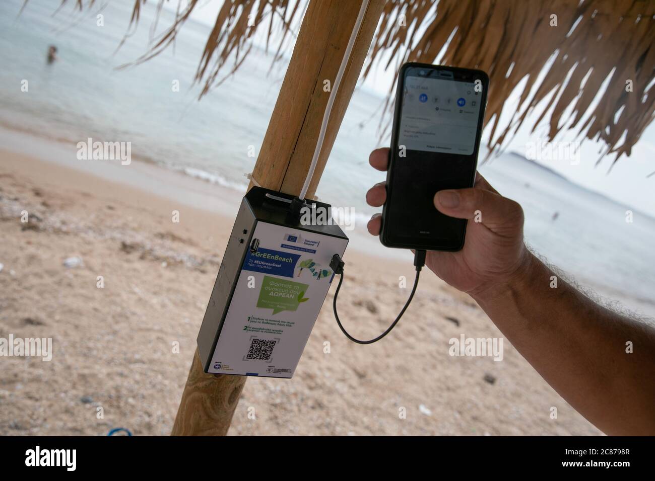 (200721) -- ATHEN, 21. Juli 2020 (Xinhua) -- das Foto vom 21. Juli 2020 zeigt ein Mobiltelefon, das über ein System von Solarmodulen und USB-Anschlüssen an einem der Sonnenschirme an einem öffentlichen Strand in der Nähe des Rathauses der Gemeinde Vari-Voula-Vouliagmeni im Süden Athens, Griechenland, aufgeladen wird. Ab Dienstag sind die Dutzende von Sonnenschirmen, die entlang des Strandes verteilt sind, gemäß den sicheren Entfernungsmaßnahmen zum Schutz gegen COVID-19, mit einem System aus Solarmodulen und USB-Anschlüssen ausgestattet, das kostenlos und umweltfreundlich aufgeladen werden kann. Unter einem Pilotprogramm am Dienstag gestartet, sunba Stockfoto