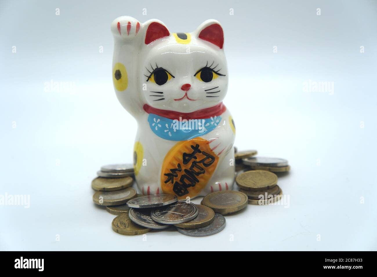 Japanische weiße Maneki Neko Glückliche Katzenbank Nahaufnahme mit Münzen Stockfoto