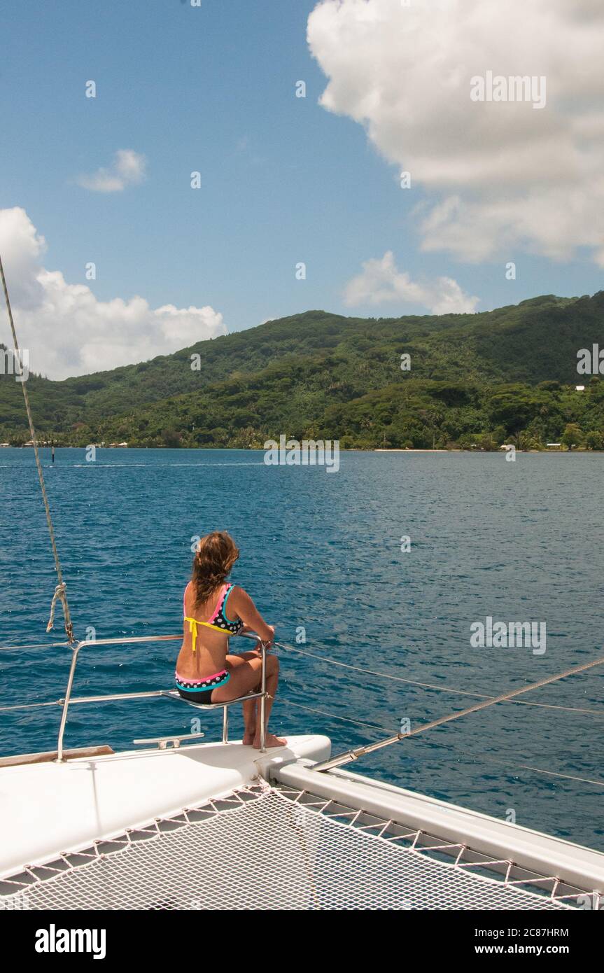 Frau, die eine Kreuzfahrt auf einem privaten Luxus-Katamaran in Französisch-Polynesien in einem Bikini mit langen Haaren und sonnengebräunten Körper. Exotisches Reiseziel. Stockfoto