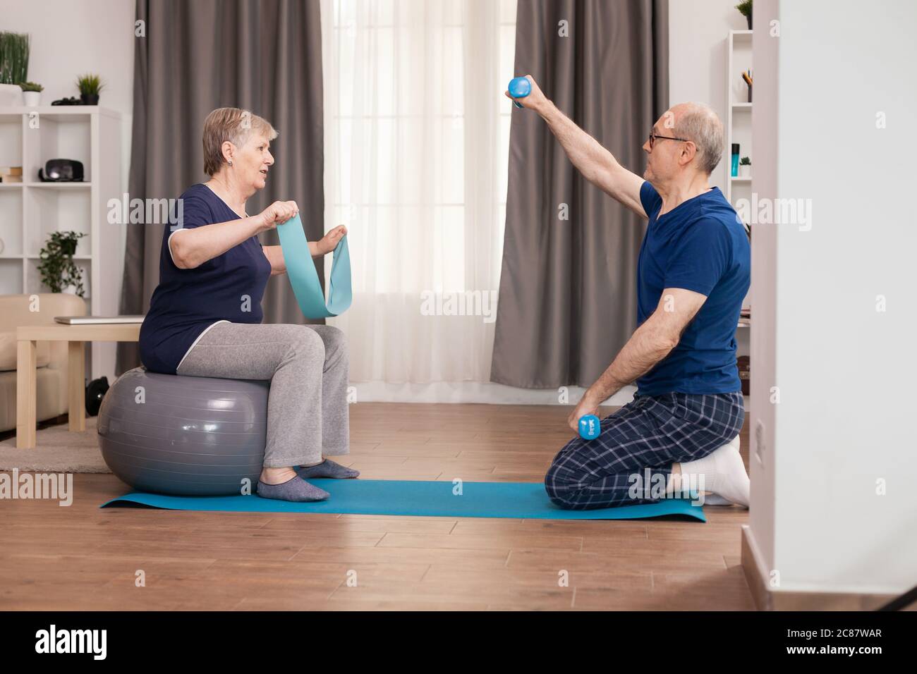 Aktive Großeltern, die zu Hause Sport treiben. Alter gesunder Lebensstil Bewegung zu Hause, Training und Training, sportliche Aktivität zu Hause auf Yoga-Matte. Stockfoto