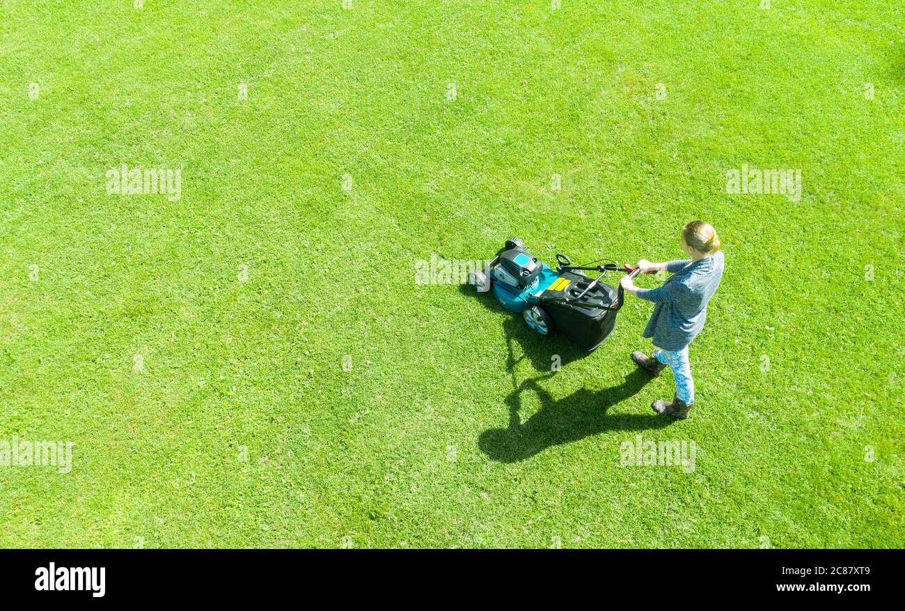 Schöne Mädchen, schneidet den Rasen. Mähen rasen. Luftaufnahme schöne Frau Rasenmäher auf grünem Gras. Mähwerk Gras. Mähen Gärtner Care arbeiten Stockfoto