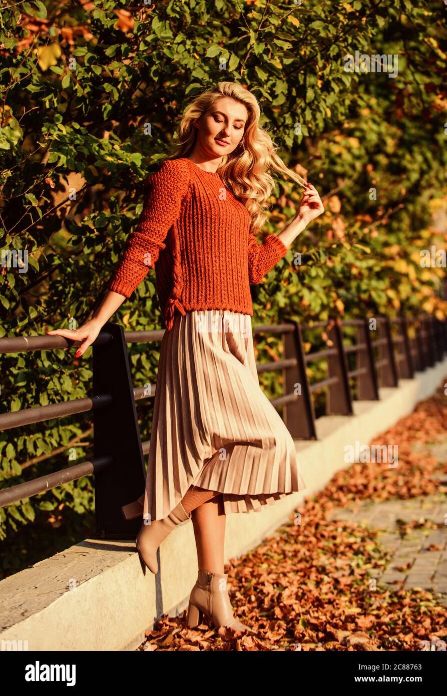 Süße lächelnde Frau. Sonniger Tag mit Blättern. Fashion Saison Herbst. Mädchen in Wellrock und Pullover. Plissierter Trend. Weibliche Schönheit. Weiblichkeit und Zärtlichkeit. Herbstfrau im Freien. Mädchen im Park. Stockfoto