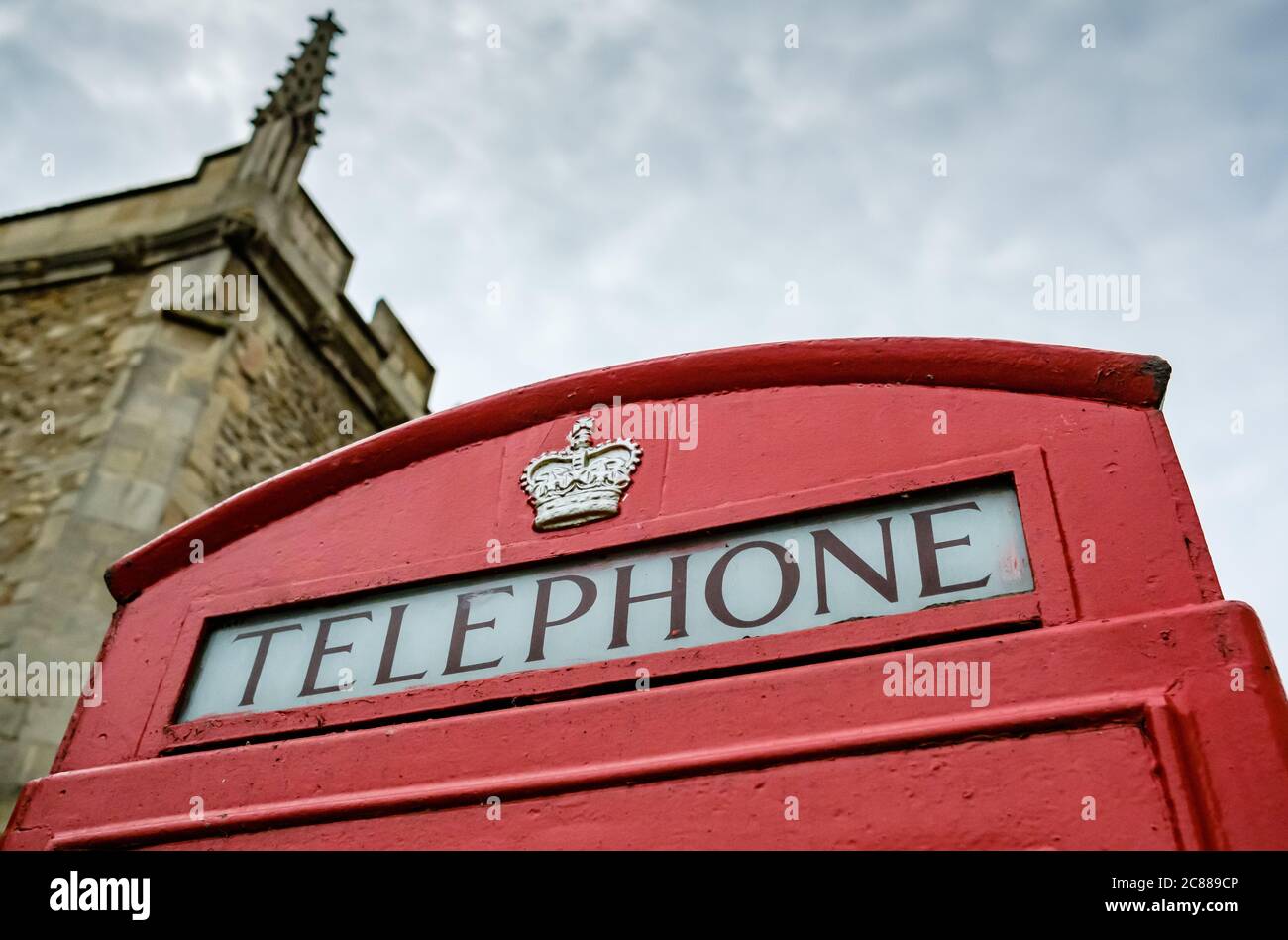 Nahaufnahme des Dachs einer altmodischen britischen roten Telefonbox, mit Schriftzug und goldlackierter Krone in der Nähe des Dachbereichs. Stockfoto