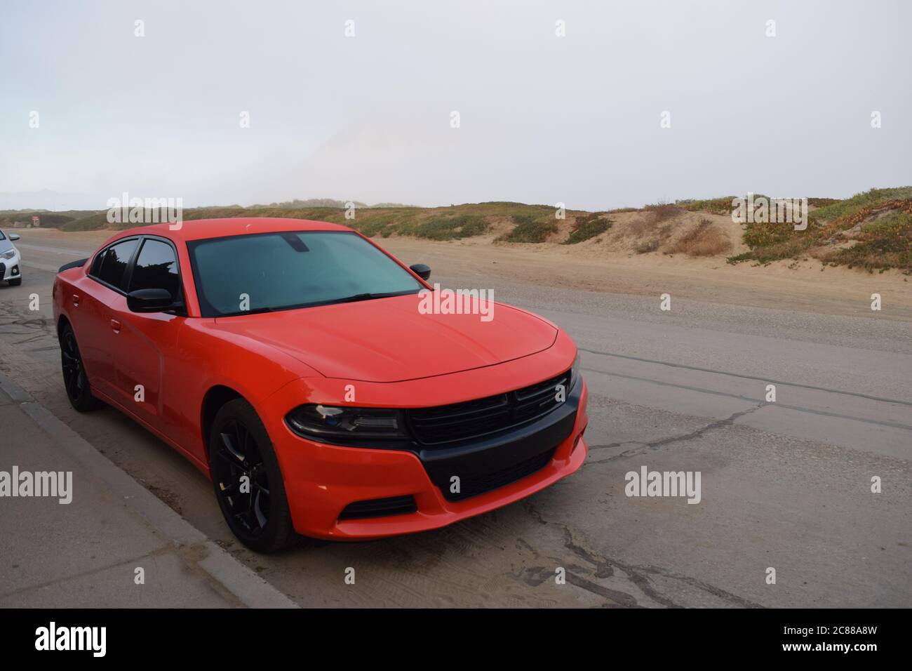 FRESNO, USA - 16. Jul 2020: Foto eines leuchtend orangefarbenen Dodge Chevy Sports Autos mit getönten Fenstern, die in den Morro Bay Dunes in Ca. Stockfoto