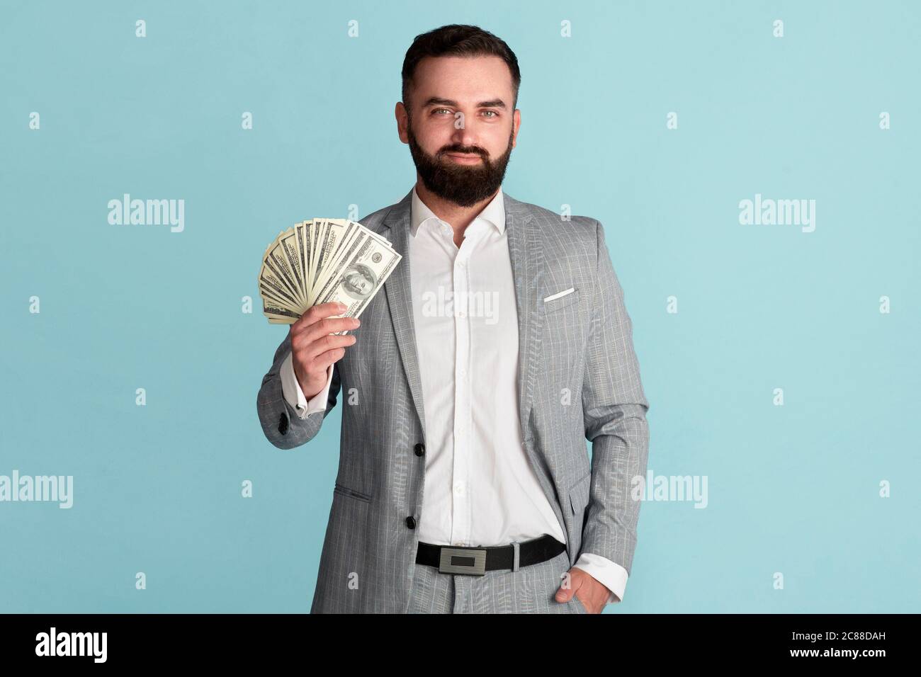 Erfolg. Wohlhabender Unternehmer zeigt amerikanisches Geld auf blauem Hintergrund Stockfoto